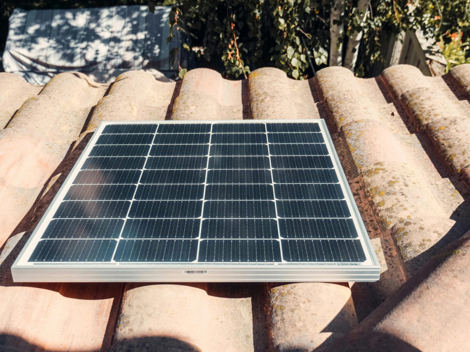 A single solar panel on a rustic tiled roof gleaming in sunlight. Eco-friendly energy.